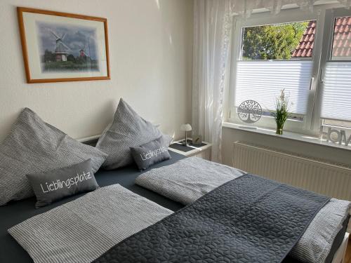 - une chambre avec un lit avec deux oreillers et une fenêtre dans l'établissement Ferienhaus Antje Greetsiel Nordsee, à Krummhörn