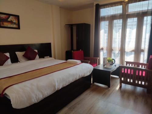 a bedroom with a large bed and a large window at Hotel The Narayani Continental in Gangtok