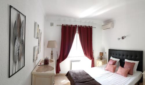 1 dormitorio con 1 cama con cortinas rojas y ventana en Le joyau Andalou, en Estepona