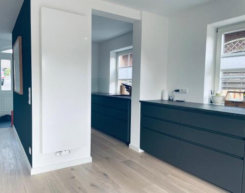 a kitchen with blue cabinets and a white wall at Sylt Seascape III in Tinnum