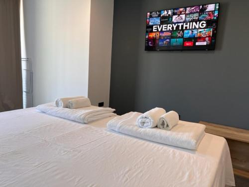 a white bed with two towels and a tv on the wall at Hotel Millenium deluxe in Selce