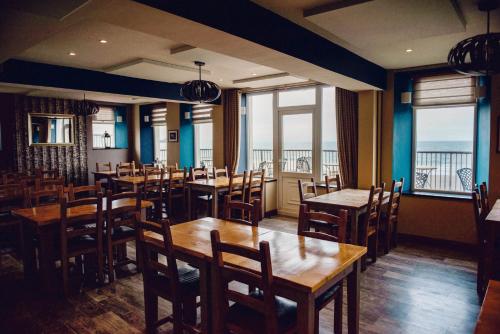 a restaurant with wooden tables and chairs and windows at Gwesty Ty Newydd in Aberdaron