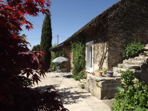ein Steinhaus mit einem Sonnenschirm und einer Terrasse in der Unterkunft L'instant... in Marolles-sous-Lignières