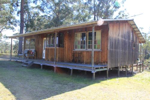 a wooden house is sitting in the grass at Lovedale Cottages Hunter Valley in Lovedale
