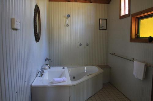 Lovedale Cottages Hunter Valley في لوفديل: حمام أبيض مع حوض ومغسلة