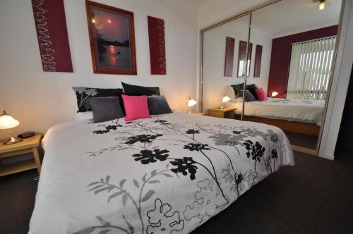 a bedroom with a black and white bed and a mirror at Beachfront Apartments in Narooma