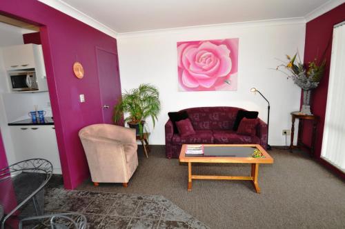 a living room filled with furniture and a red couch at Beachfront Apartments in Narooma