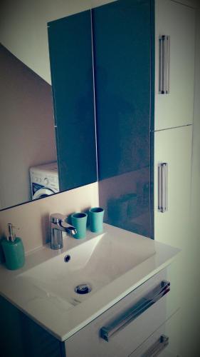 La salle de bains est pourvue d'un lavabo avec miroir et de tasses bleues. dans l'établissement TY Maelou, à Ploemeur