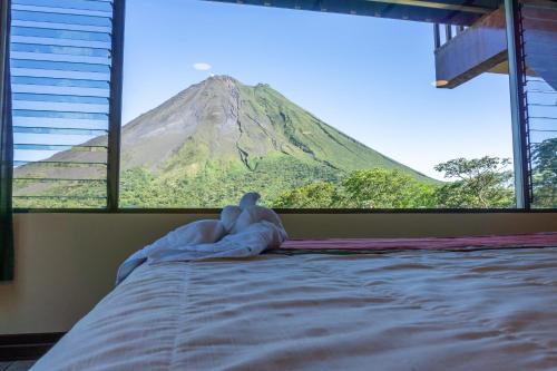 una persona acostada en una cama con vistas a la montaña en Arenal Observatory Lodge & Trails, en Fortuna