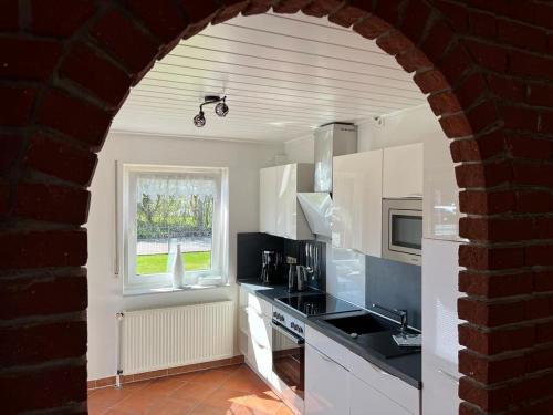 クルムホルンにあるFerienhaus Antje Greetsiel Nordseeの白いキャビネットと窓のあるキッチン