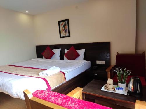 a bedroom with two beds with red pillows and a table at Hotel The Narayani Continental in Gangtok