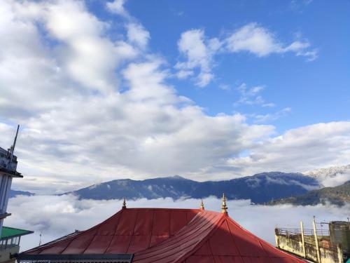 a red tent with a view of clouds and mountains at Hotel The Narayani Continental in Gangtok