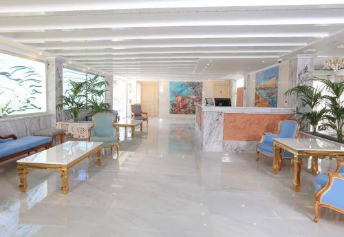 a lobby with tables and chairs and paintings on the wall at Cavomarina Beach- Adults Only in Kavos
