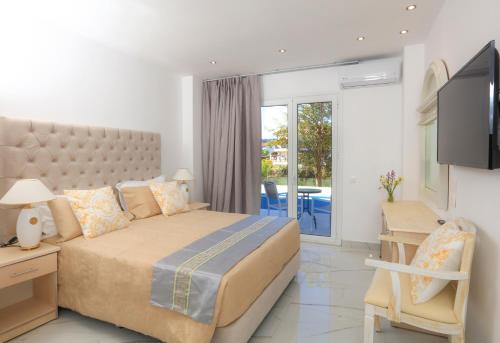 a bedroom with a large bed and a balcony at Cavomarina Beach- Adults Only in Kavos