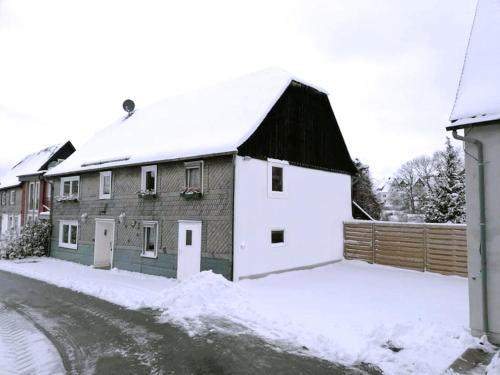 a house with a black roof in the snow at Haus Bornstein in Olsberg