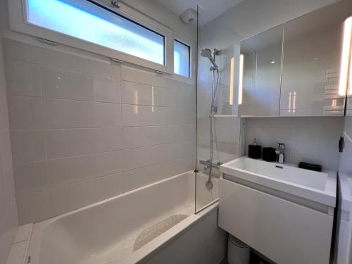 ラ・クリュサにあるElan 12 - Très bel appartement centre villageの白いバスルーム(シンク、バスタブ付)、窓が備わります。