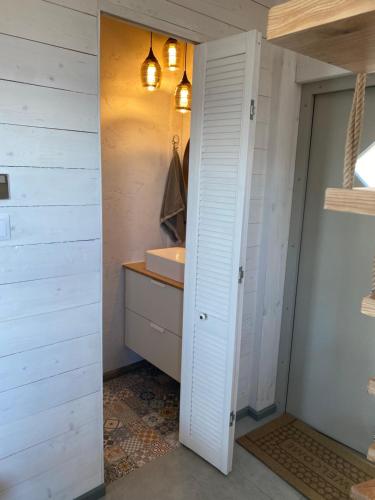 een badkamer met een wastafel en een witte deur bij Vila Preiloja - Žvejo namelis in Neringa