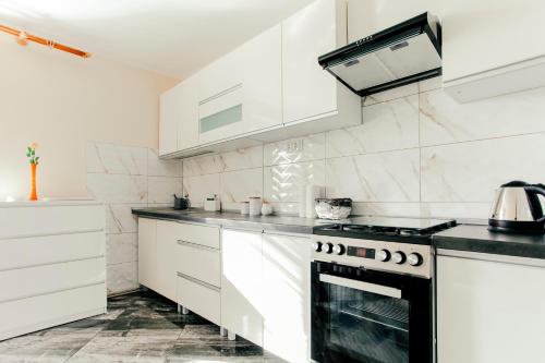 a kitchen with white cabinets and a stove top oven at Serce Darłówka in Darłowo