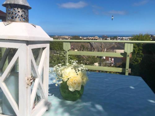 a vase of flowers on a table next to a lantern at ORCHARD HILL HOUSE Apartment in Paignton