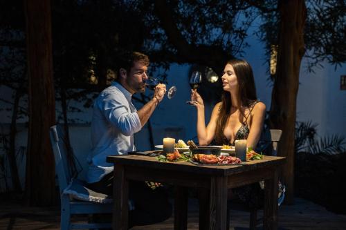a man and woman sitting at a table drinking wine at Can Vistabella Boutique Resort in San Antonio