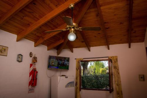 Habitación con ventilador de techo y nevera. en Cabañas El Sauce Mina Clavero, en Mina Clavero