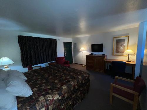 a hotel room with a bed, desk, chair, and lamp at Spinning Wheel Motel in Baraboo