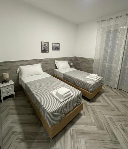 2 aparte bedden in een kamer met houten vloeren bij Holiday Rooms Rho in Rho