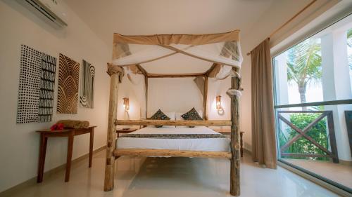 a bedroom with a canopy bed and a window at Sansi Kendwa Beach Resort in Kendwa