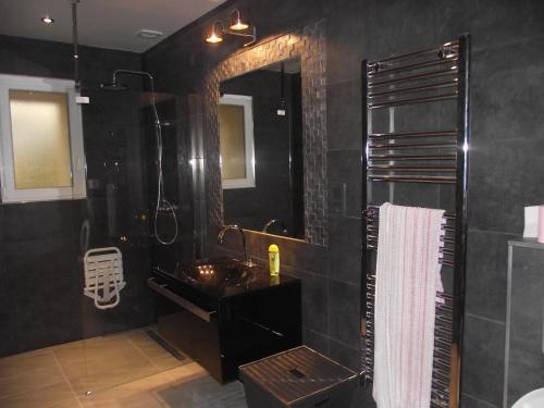 une salle de bain noire avec un lavabo et un miroir dans l'établissement Nature & Chateaux, à Villandry