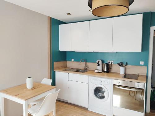 une cuisine avec une machine à laver et une table dans l'établissement Magnifique studio face au parc thermal, à Thonon-les-Bains