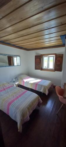 two beds in a room with wooden ceilings at Portela Guesthouse in Cercal