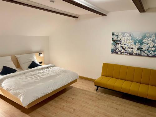 ein Schlafzimmer mit einem Bett und einem gelben Sofa in der Unterkunft Chalet an der Donau direkt bei Regensburg, 5 Sterne DTV in Pentling