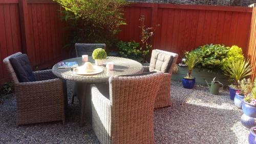 a patio with a table and wicker chairs at Bossell Cottage Devon in Buckfastleigh