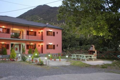 a pink house with a picnic table in front of it at Artemis Apartments in Konitsa