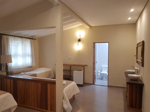 a bedroom with two beds and a bathroom with a sink at Gamboa Eco Refugio Pousada in Iporanga
