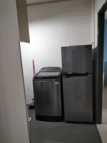 a refrigerator and a trash can in a room at Homestay pangsapuri sutera seberang jaya in Kampong Telok
