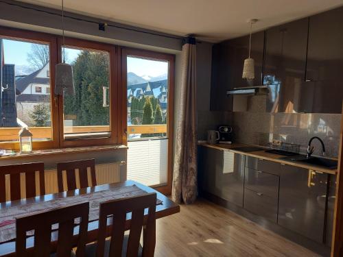 a kitchen with a table and a large window at Apartament Zakopane Kamieniec 10i in Zakopane