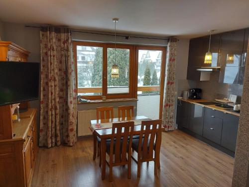 a kitchen with a table and chairs and a window at Apartament Zakopane Kamieniec 10i in Zakopane