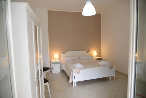 een slaapkamer met een wit bed en 2 lampen bij Casa Angelina in Monopoli