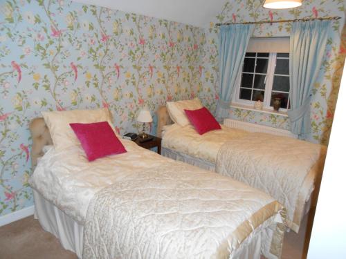 two beds in a bedroom with floral wallpaper at No. 26 in Wells