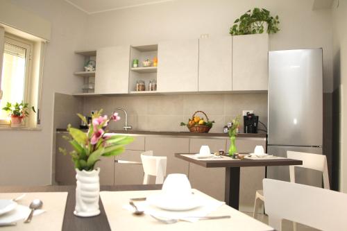 una cucina con armadi bianchi, tavolo e frigorifero di B&B Delle Serre a Messina