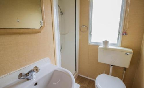 ein Badezimmer mit einem weißen WC und einem Waschbecken in der Unterkunft Willerby Magnum in Clacton-on-Sea
