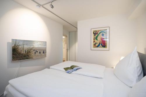 um quarto branco com 2 camas e um quadro na parede em Zweite Heimat em Westerland