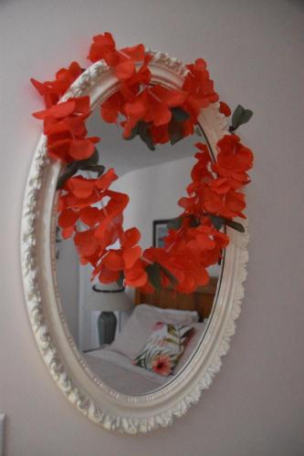 a mirror with a red flower wreath on a wall at Seabank House Bed and Breakfast Aloha in Pictou