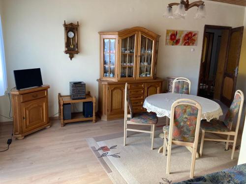 ein Wohnzimmer mit einem Tisch, Stühlen und einer Uhr in der Unterkunft PBJ Apartman in Pilisborosjenő