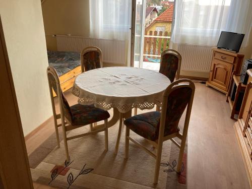 einen Esstisch mit 4 Stühlen und einem weißen Tisch in der Unterkunft PBJ Apartman in Pilisborosjenő