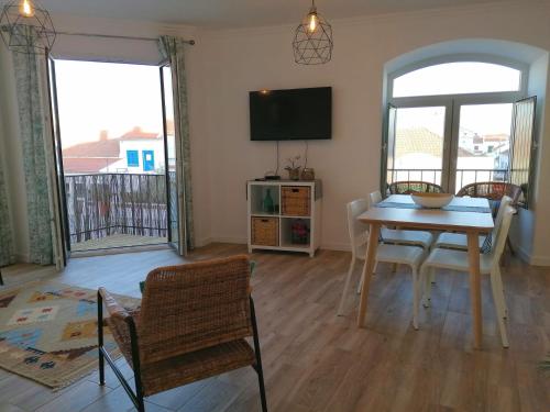 a living room with a table and chairs and a television at Apartamento Vilamar in Vila Nova de Milfontes