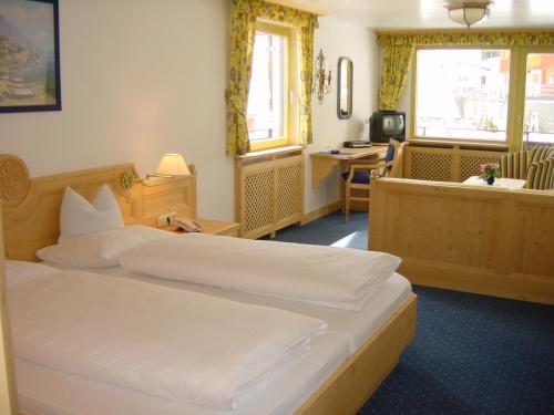a hotel room with two beds and a desk at Muntanella in Lech am Arlberg