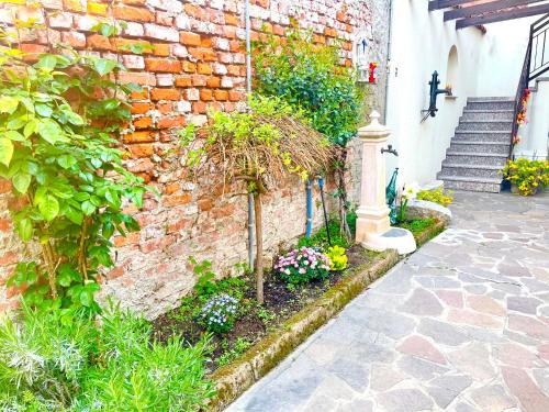 a brick building with a garden with flowers and a pillar at B&B Corte sul Naviglio CIN I T 0 1 5 0 7 0 C 1 3 X U I L Q C V in Cernusco sul Naviglio