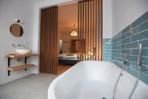 a bathroom with a bath tub and a bedroom at Gastenkamers huYze K in Zottegem